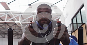 African american man wearing lowered face mask exercising at gym