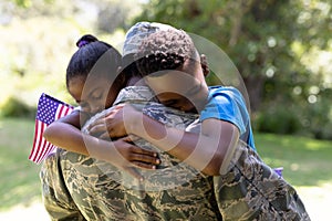 African American man wearing a military uniform holding his children
