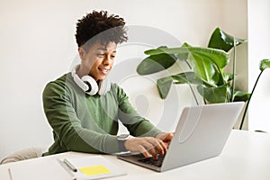 African american man in wireless headphones studying online on laptop