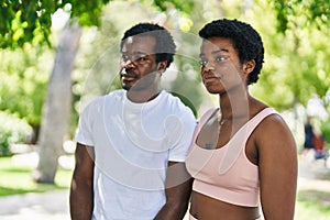 African american man and woman couple standing together with serious expression at park