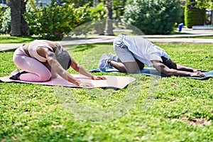 African american man and woman couple stretching back at park
