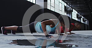 African american man and woman doing push ups in an empty urban building