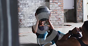 African american man and woman exercising with medicine ball in an empty urban building