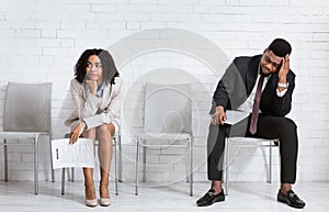 African American man and woman feeling exhausted from waiting for job interview at office hall, panorama