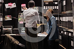 African american man and woman investigators studying evidence photographs