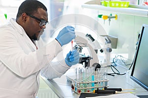 African-american man working in lab. Scientist doctor making medical research. Laboratory tools: microscope, test tubes