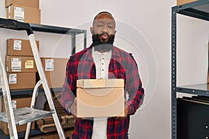 African american man working at small business ecommerce looking at the camera blowing a kiss being lovely and sexy