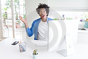 African American man working using computer celebrating crazy and amazed for success with arms raised and open eyes screaming