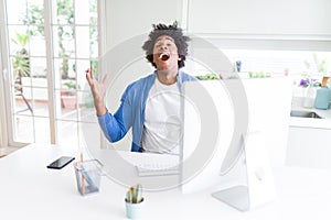 African American man working using computer celebrating mad and crazy for success with arms raised and closed eyes screaming