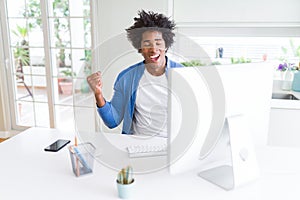 African American man working using computer very happy and excited doing winner gesture with arms raised, smiling and screaming