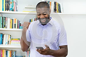 African american mature adult businessman receiving message with good news at phone