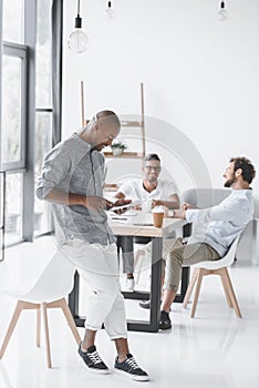 african american man using tablet while colleagues discussing strategy at workplace photo