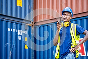 African american men worker Check and control loading freight Containers by use radio at commercial shipping dock feeling curious