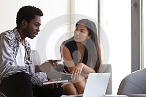 African American mentor training Asian intern, using laptop photo