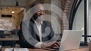 African American middle-aged entrepreneur smiling happy laughing positive typing laptop computer ethnic business man