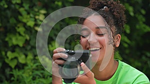 African American mixed race biracial teenager young woman using a digital camera outside taking photographs