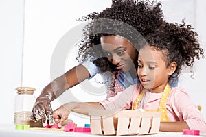 african american mom and daughter making cookies with cookie