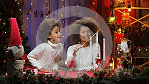 African American mom and little daughter burning white candles with wow delight emotions. Woman and girl sitting near