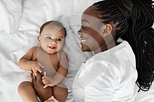 African American mom lying in bed with her cute infant