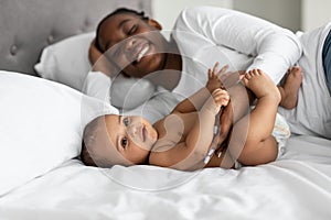 African American mom lying in bed with her sweet baby