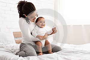 African American Mommy Cuddling Her Lovely Baby Son Sitting Indoors