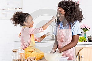 african american mother and daughter having fun while making dough