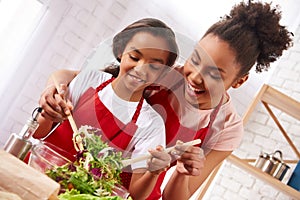 African American mother and daughter mix salad