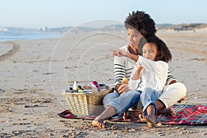 African American mother and daughter on picnic on beach