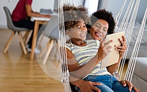 African american mother and daughter watching entertainment on digital tablet at home