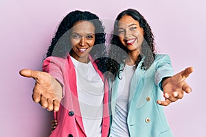 African american mother and daughter wearing business style smiling friendly offering handshake as greeting and welcoming