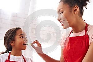 African American mother is feeding small daughter