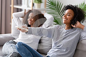 African American mother holding remote controller, relaxing with daughter