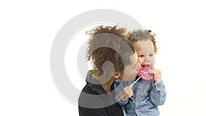 African american mother holds a son, licking a candy and kissing a baby. White background. Slow motion