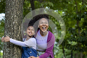 African American mother is playing together with her young daughter while having a summer picnic in the public park for wellbeing