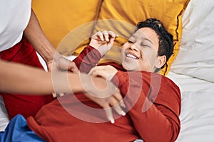 African american mother and son doing tickle lying on bed at bedroom