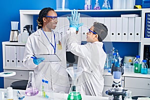 African american mother and son scientists smiling confident high five with hands raised up laboratory
