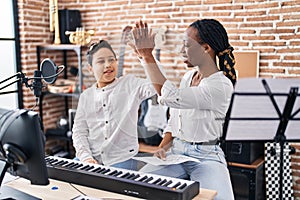 African american mother and son student and teacher with hands raised up at music studio
