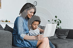 african american mother and son using laptop together