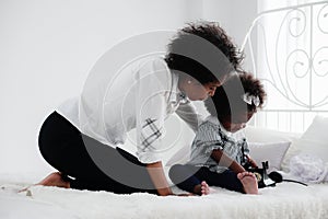 African american mother watching her girl child palying  telephone in bedroom