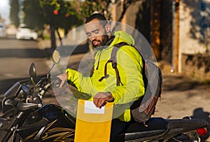 African American motorcycle courier on motorbike with envelope for delivery