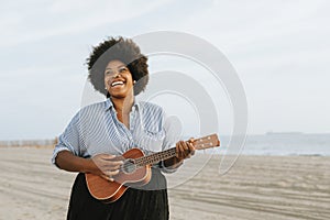 African American musician playing ukulele at the beach