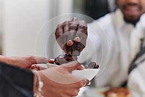 African American Muslim man delicately takes dates to break his fast during the Ramadan month, seated at the family