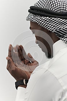 African American Muslim man raises his hands in prayer, seeking solace and devotion to God, as he stands isolated