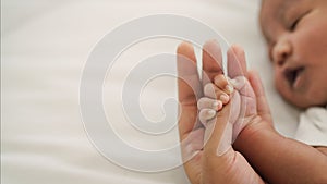 African american new born baby hand holding mom finger on white bed