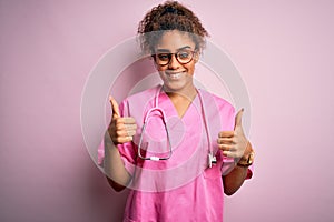 African american nurse girl wearing medical uniform and stethoscope over pink background success sign doing positive gesture with