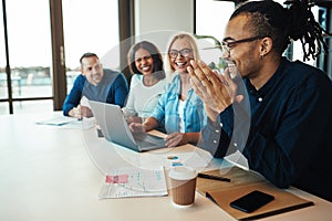 African American office worker laughing with colleagues in a mee