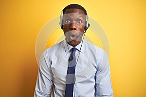 African american operator man working using headset over isolated yellow background afraid and shocked with surprise expression,