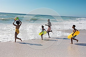 African american parents and children playing together at beach on sunny day