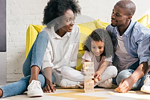 african american parents and daughter playing blocks tower game together