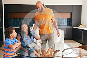 African American Parents Helping Son Studying Homework On Digital Tablet In Kitchen